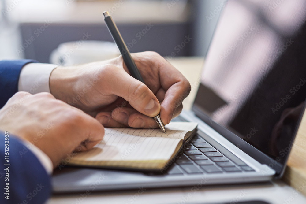 Poster the image focuses on a man's hand scribbling in a notepad on a stylish laptop, set against a blurry 