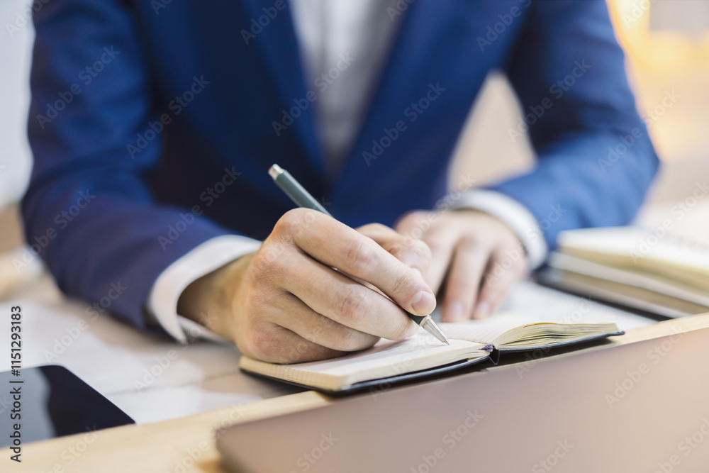 Poster Close-up capture of a man's hand as he writes in a notepad, with an out-of-focus background