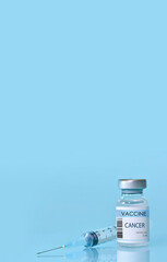 Cancer Vaccine in a bottle with a syringe on a blue background. Experimental cancer vaccine vial for immunization against Cancer disease.Copy space