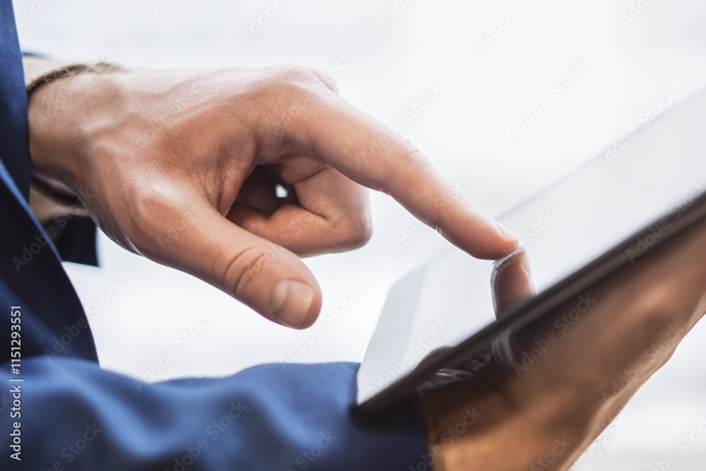 Poster close detail of a man's finger navigating the screen of an advanced tablet on a desk, set against th