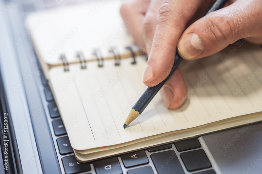 Poster closeup illustration of a man's hand engaged in writing in a notepad on a stylish laptop, with a sof