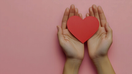 Fototapeta premium Hands holding a red heart on pink background symbolizing love and care