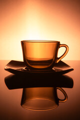 One Glassed Teacups or Coffee Cup With Plate Isolated Over Glowing Warm Orange  Gradient Background.