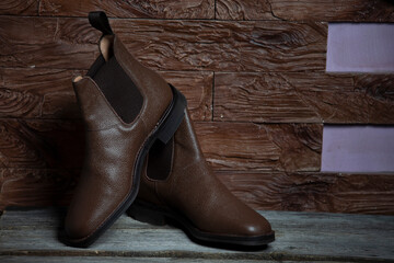 Footwear Concepts. Pair of Brown Classic Shagreen Leather Chealsea Boots As Still Life Concepts Placed Near One Another Over Stony Background.