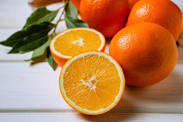 Fresh oranges on a light table. Half an orange next to whole ones