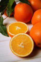 Fresh oranges on a light table. Half an orange next to whole ones