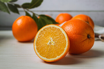 Fresh oranges on a light table. Half an orange next to whole ones
