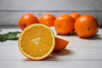 Fresh oranges on a light table. Half an orange next to whole ones