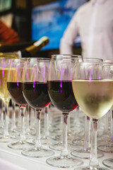 A beautifully arranged collection of wine glasses filled with red and white wines, set on a white tablecloth