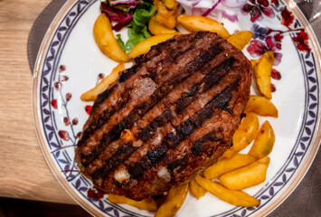 Close-up Top View Of Grilled Homemade Hamburger with roasted potatoes, Old Rough Wooden Rustic Table In The Background. Meal Concept