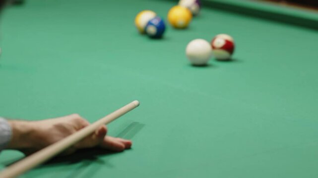 Over shoulder slowmo shot of unrecognizable snooker player aiming at cue ball and striking billiard ball, failing to sink it in hole during play