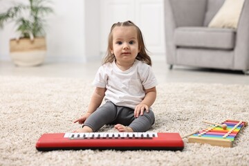 Cute little girl playing with toy piano at home