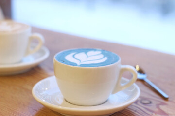 Blue matcha tea in a white mug on a table in a cafe