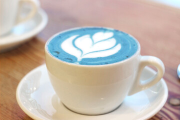 Blue matcha tea in a white mug on a table in a cafe