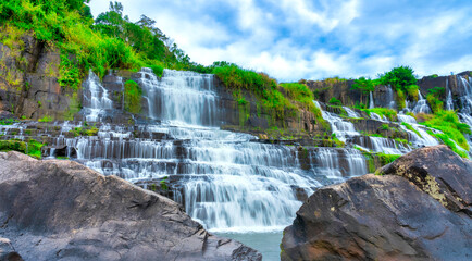 Naklejka premium Mystical waterfall with foreground is autumn leaves in the Da Lat plateau, Vietnam. This is known as the first Southeast Asian waterfall in the wild attracted many tourists to visit
