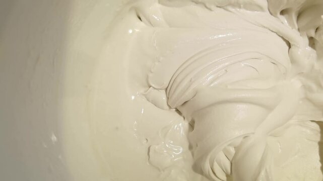 Smooth mixing process of creamy batter in large bowl captured in high definition closeup sequence.