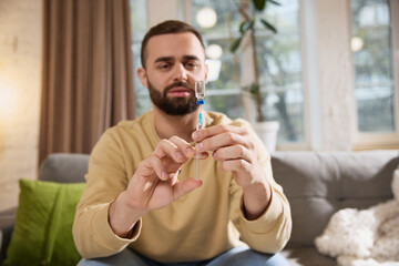 Focused man draws solution for injection into syringe preparing to injecting treatment at home. Concept of illness, health insurance, medication, pharmaceutical, medicine. Ad.