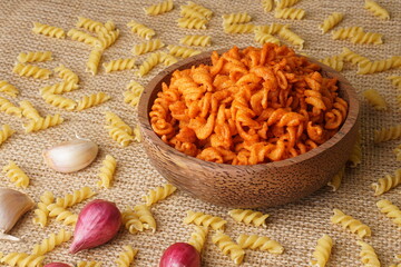 Spicy fried small macaroni crackers, on a brown cloth background, flat lay or top view, with studio lighting