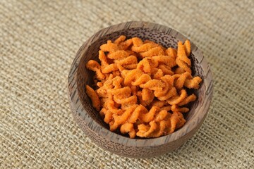 Spicy fried small macaroni crackers, on a brown cloth background, flat lay or top view, with studio lighting