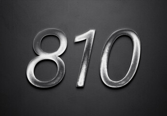 Chrome metal 3D number design of 810 on grey background.