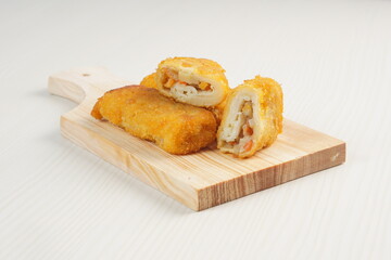 vegetables risoles enclosed in crepe-like wrappers and rolled into bread crumbs and fried. served on wood plate. perfect for recipe, article, catalogue, promotion, or any cooking contents.