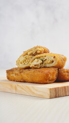 chicken rissoles enclosed in crepe-like wrappers and rolled into bread crumbs and fried. served on wood plate. perfect for recipe, article, catalogue, promotion, or any cooking contents.
