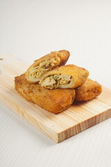 chicken rissoles enclosed in crepe-like wrappers and rolled into bread crumbs and fried. served on wood plate. perfect for recipe, article, catalogue, promotion, or any cooking contents.
