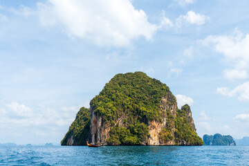 Obraz premium Un bateau touristique à longue queue passe devant un îlot karstique en Thaïlande