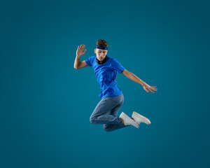 Handsome skater jumping on light blue background