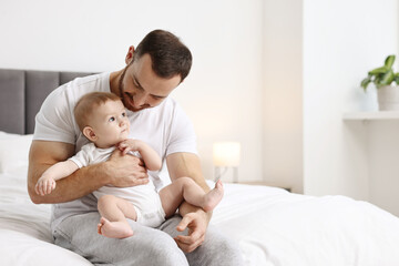 Father with his little baby on bed at home. Space for text