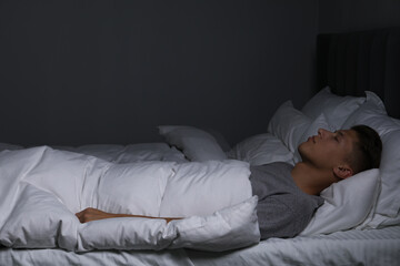 Young man sleeping in soft bed at night