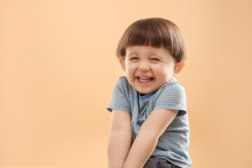 Portrait of happy little boy on beige background. Space for text