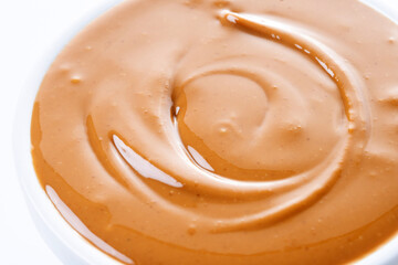 Peanut butter in a bowl isolated on white background. Close up