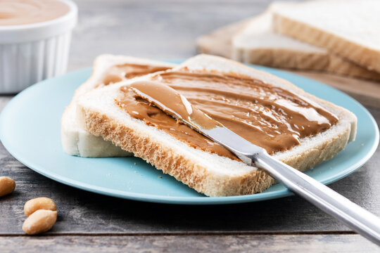 Bread toast with peanut butter cream on wooden table