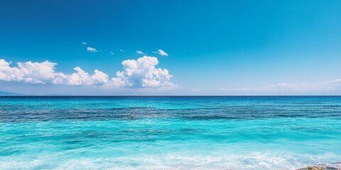 Fototapeta premium Vibrant blue sea and sky create a stunning scene, showcasing the clear ocean waves against a backdrop of the bright blue sky, highlighted by selective focus on the tranquil blue sea.