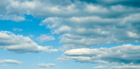 Photo of fluffy white clouds and bright blue sky.