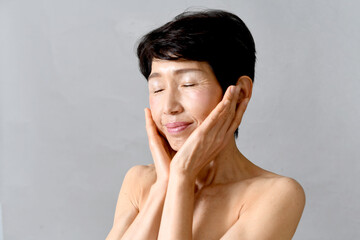 両手で頬を包む中高年のアジア人女性