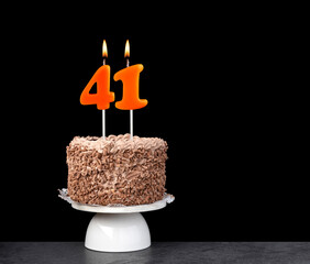 Birthday card with candle number 41 - Chocolate cake on black background.