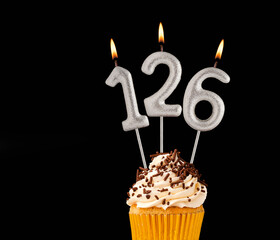 Birthday cupcake on black background - Number 126 shaped candles.