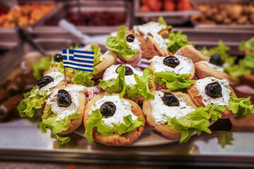 Appetizing Greek gyros with tzatziki sauce, fresh lettuce, and olives served on pita bread, adorned with a Greek flag, symbolizing authentic Mediterranean flavors.