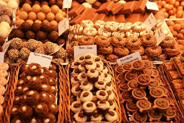 a variety of artisan chocolates and truffles at a market, including selections named Petit Cappuccino and Bonbon Fiorentino, beautifully arranged in baskets.