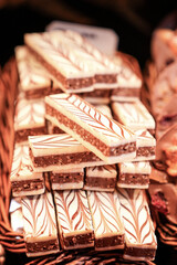 Elegant assortment of layered marzipan bars, beautifully decorated with white and dark chocolate swirls, artfully displayed in a rustic basket, ideal for gourmet gifting.