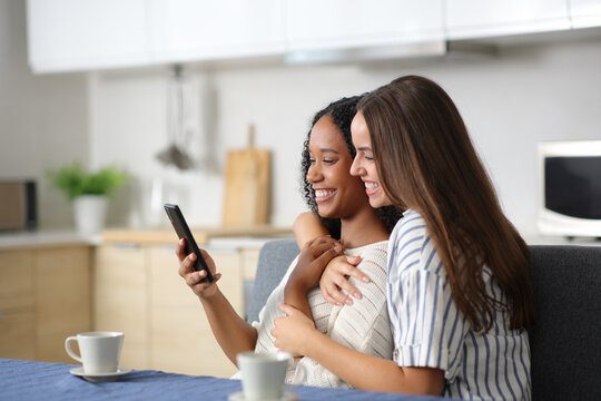 Happy lesbian couple using phone together