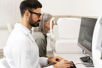 Obraz premium Optometrist analyzing eyesight test results on computer in ophthalmology clinic