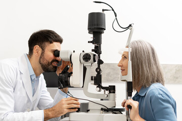 Ophthalmologist examining senior patient's eyes with slit lamp in clinic