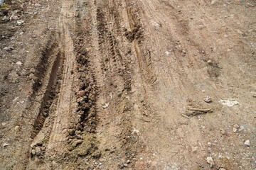 Deep tires tracks on the road covered by wet muddy sand