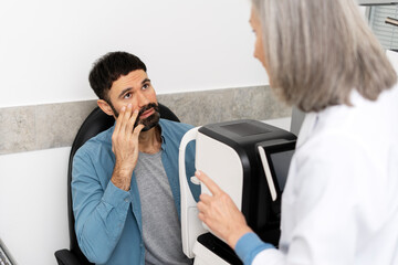 Ophthalmologist performing eye exam on patient using autorefractor