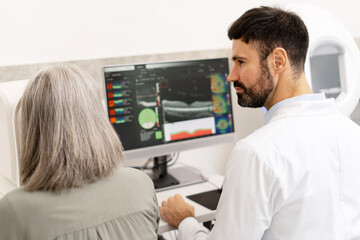 Ophthalmologist showing eye exam results to senior patient on computer