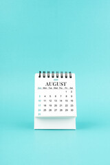 August 2025 white desk calendar on blue background.