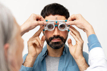 Optometrist examining patient's eyesight with phoropter during eye exam